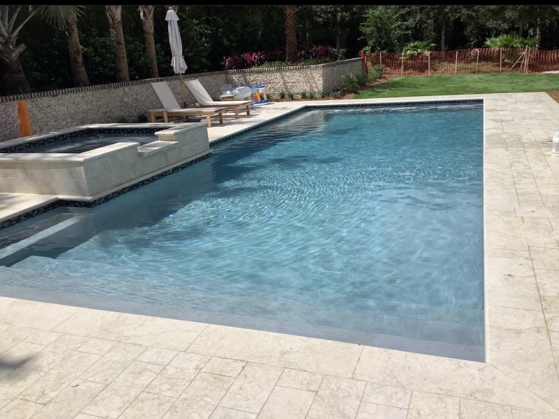 EMV clear blue swimming pool with attached spa and stone pavers